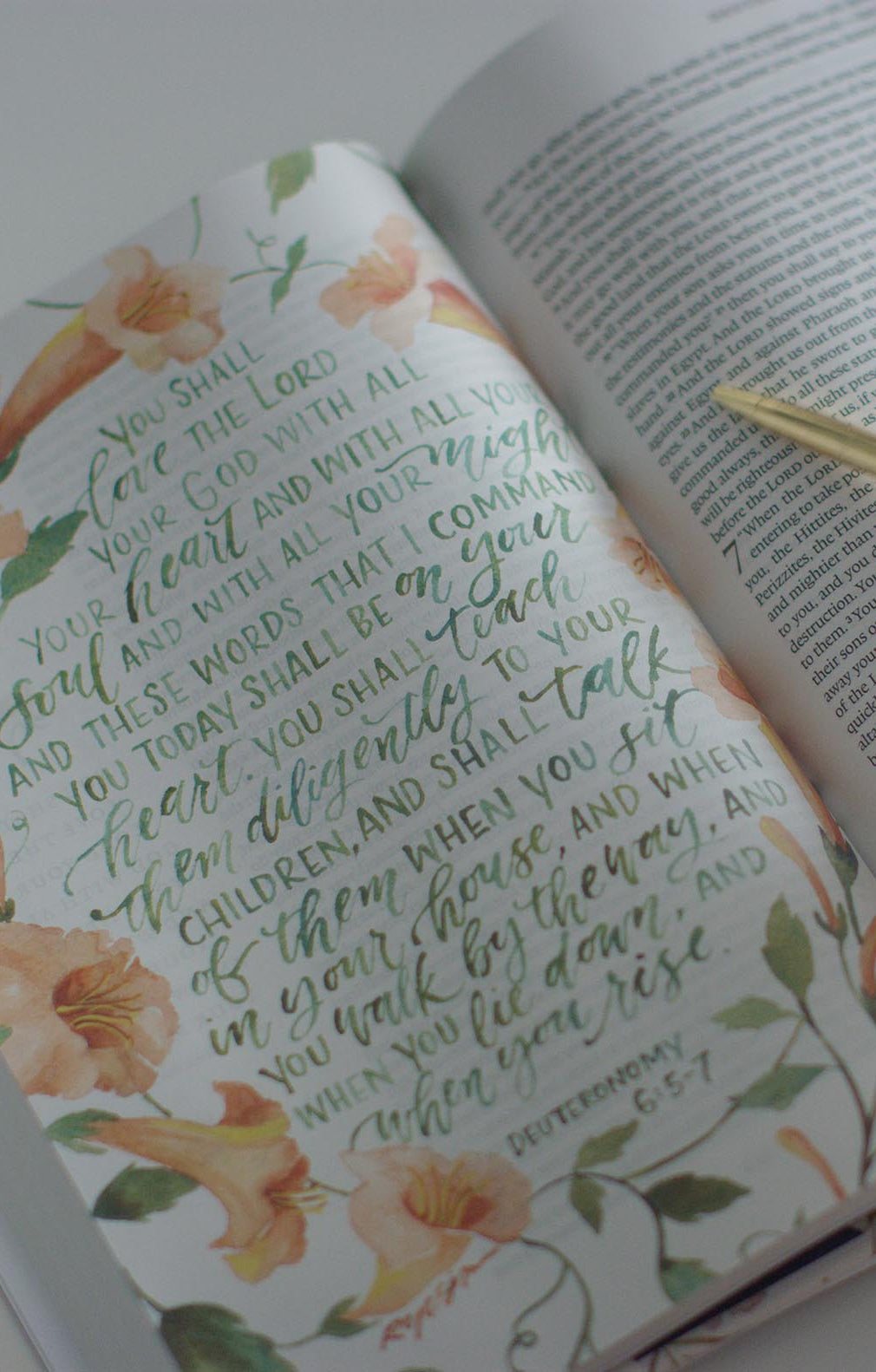 An interior page of the GraceLaced. Deuteronomy 6:5-7 has been turned into a full-page artwork, written in green and surrounded by peach-colored flowers.