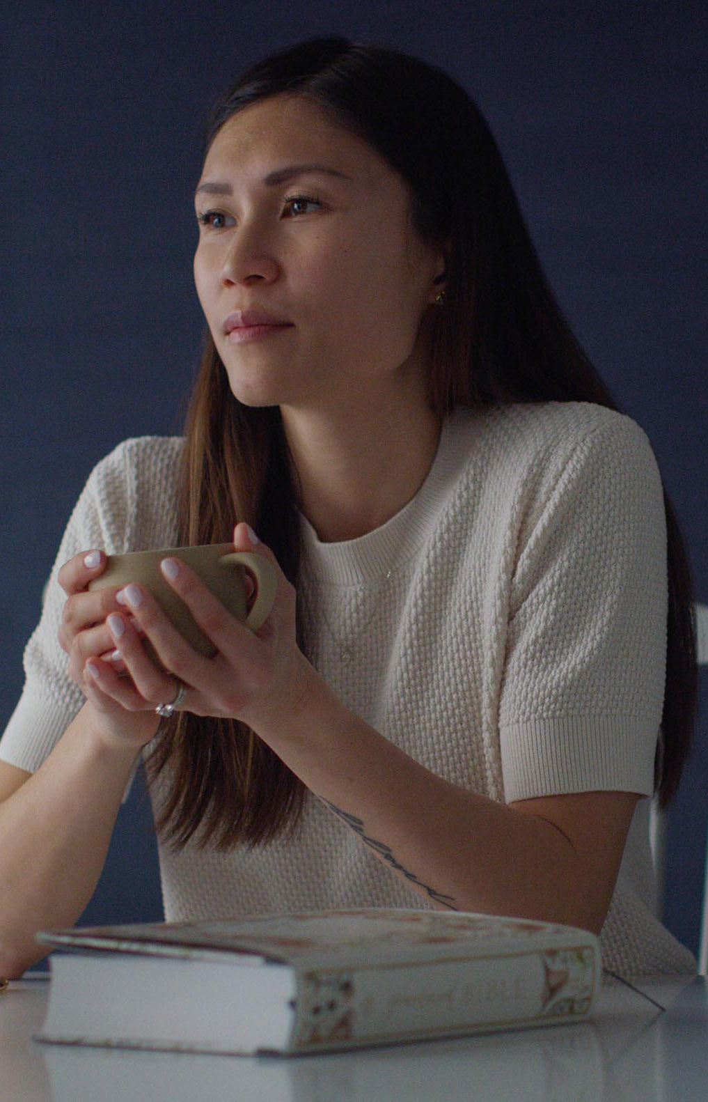 An image of a woman holding a coffee cup while sitting next to a copy of the Gracelaced Bible.