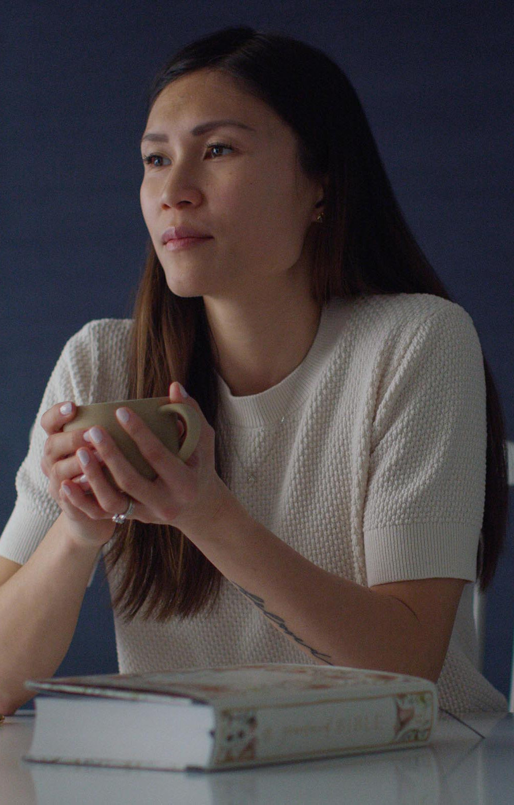 An image of a woman holding a coffee cup while sitting next to a copy of the Gracelaced Bible.