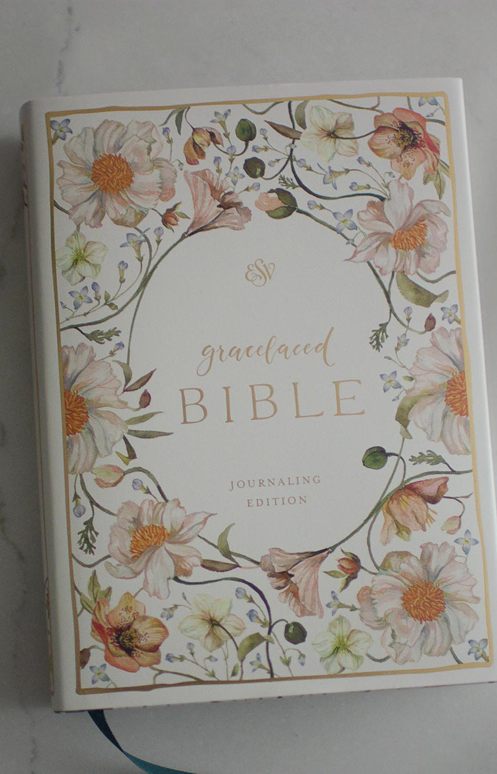 The cover of the Gracelaced Bible, Journaling Edition (hardcover). Pink, yellow, and green flowers surround the title of the Bible in a golden script.
