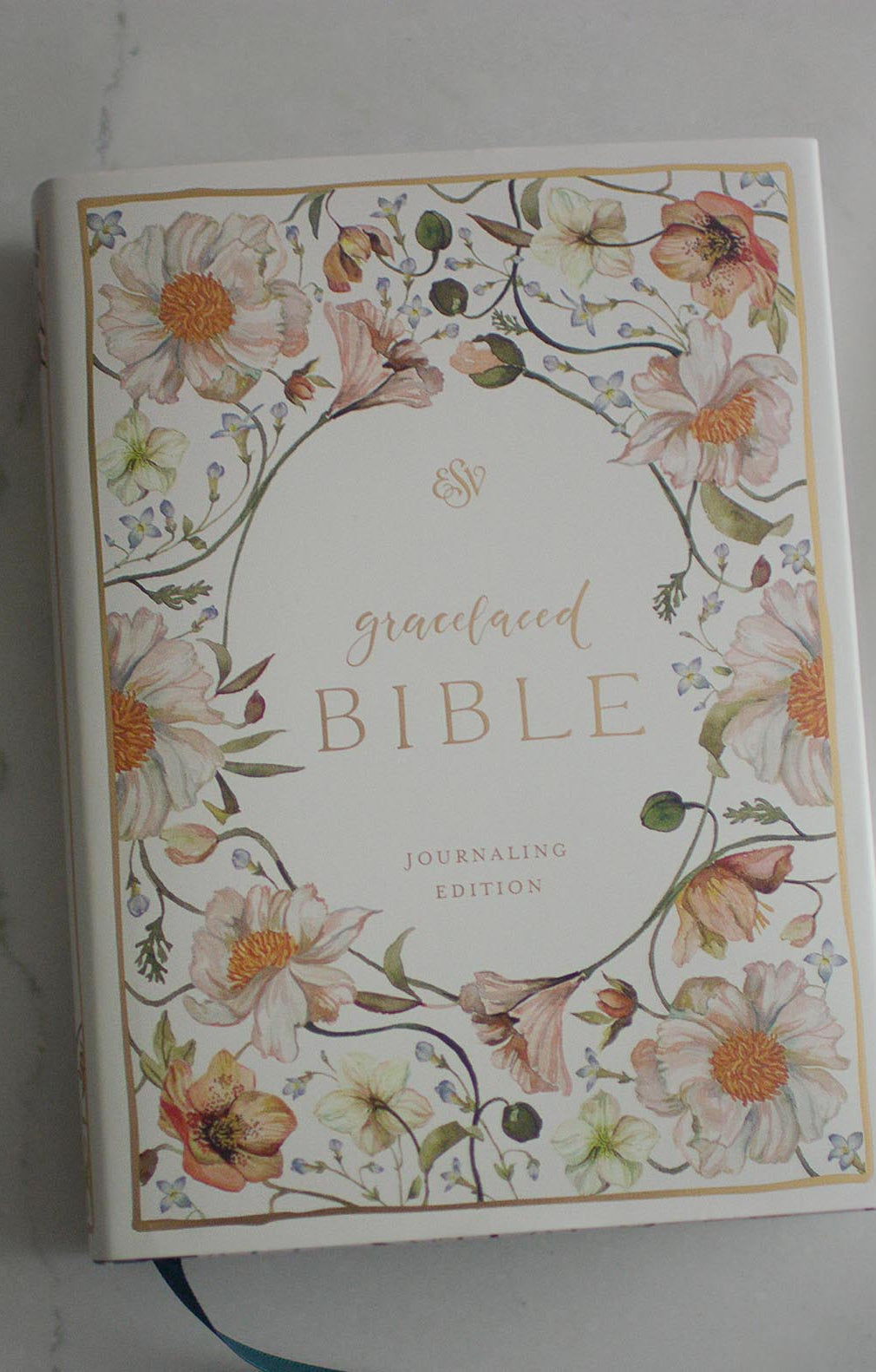 The cover of the Gracelaced Bible, Journaling Edition (hardcover). Pink, yellow, and green flowers surround the title of the Bible in a golden script.