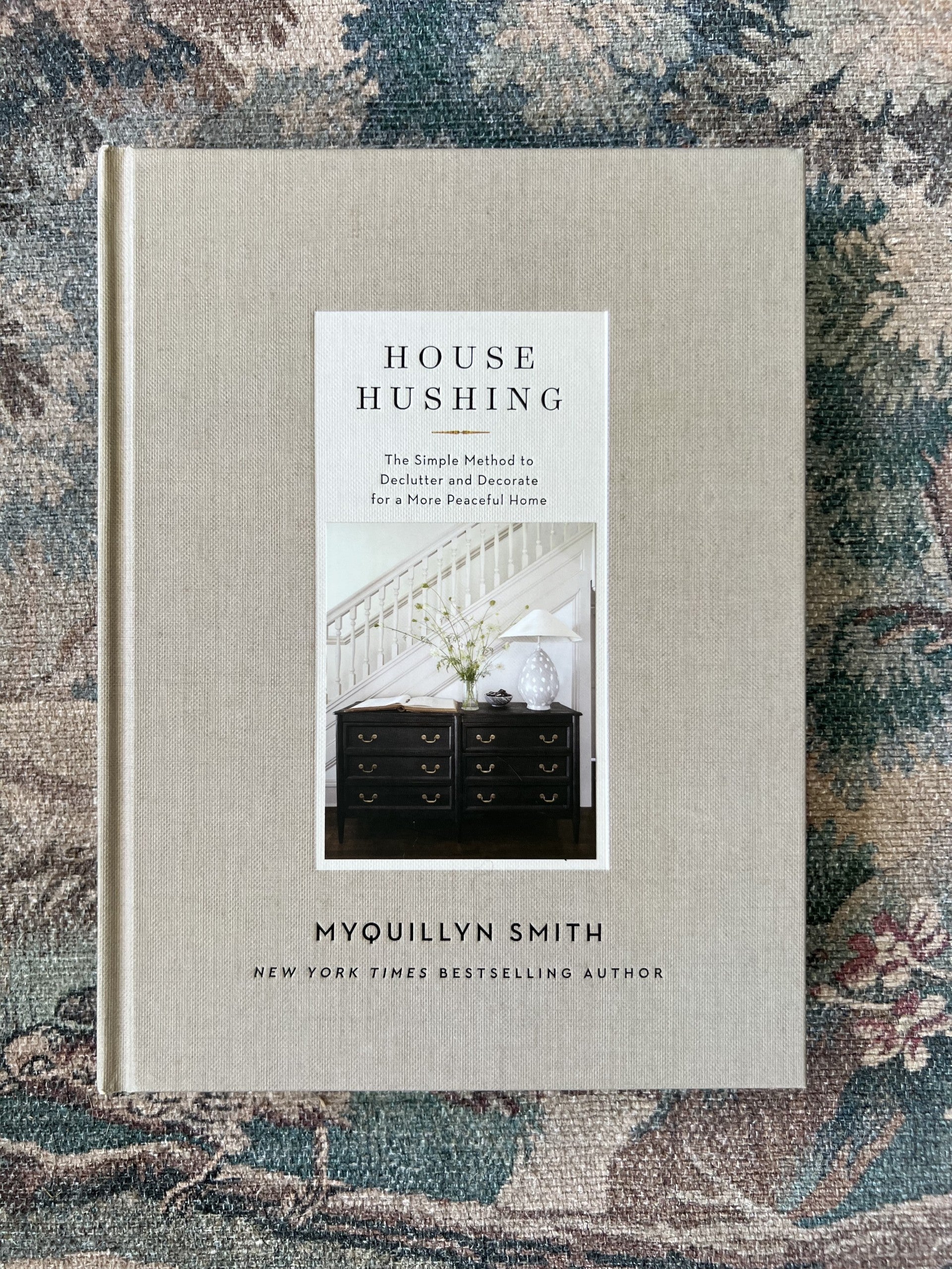 The cover of "House Hushing" sitting on floral tablecloth.