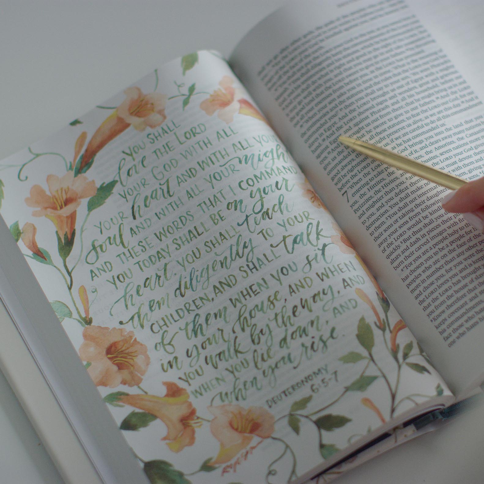 An interior page of the GraceLaced. Deuteronomy 6:5-7 has been turned into a full-page artwork, written in green and surrounded by peach-colored flowers.