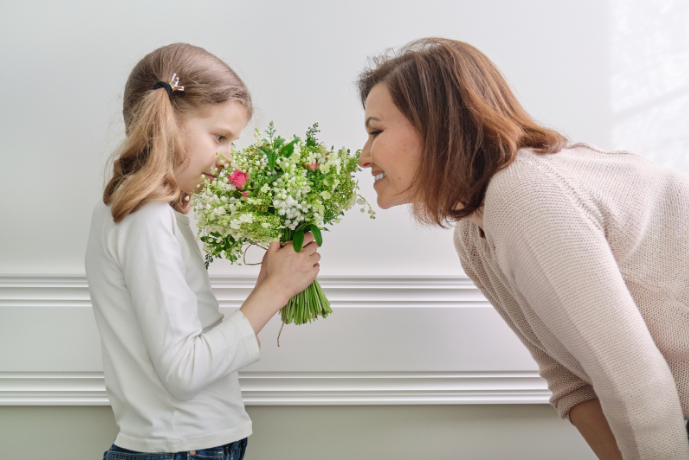 A photo of a young girl giving a bouquet of flowers to her mother.